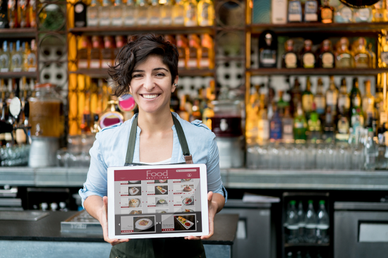 iStock-525498662 — Woman Holding Tablet in front of Bar — XXL iStock-525498662 -- Woman Holding Tablet in front of Bar -- XXL